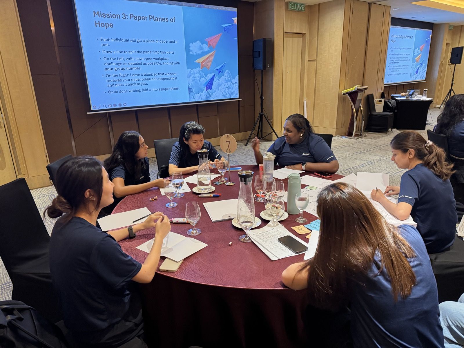 Teams working on a paper planes mission at their tables
