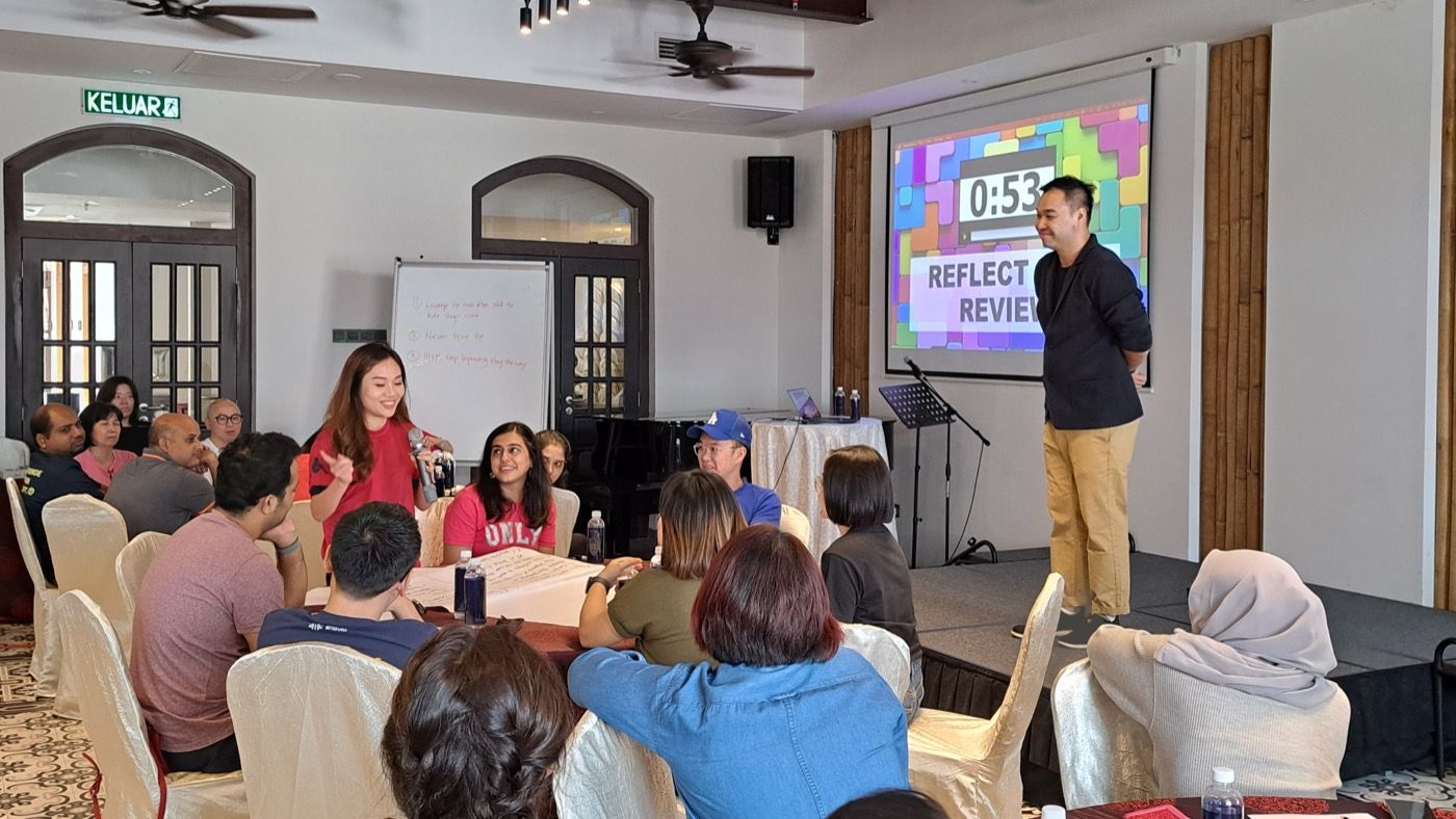 Edward Chan leading a reflect-and-review session with a corporate team